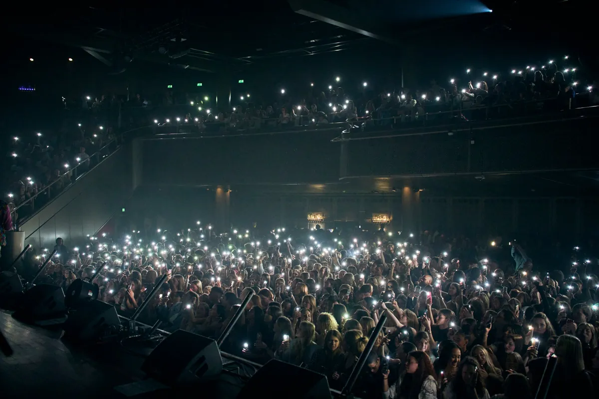 A full venue lit up by phone lights during a Broederliefde show